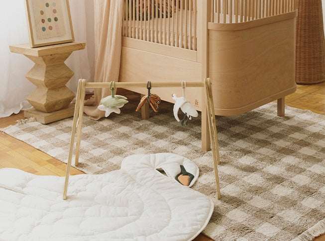 Wood Play Gym with Three baby rattle hangers shaped like a swan, butterfly, and water lily pad on a swan play mat
