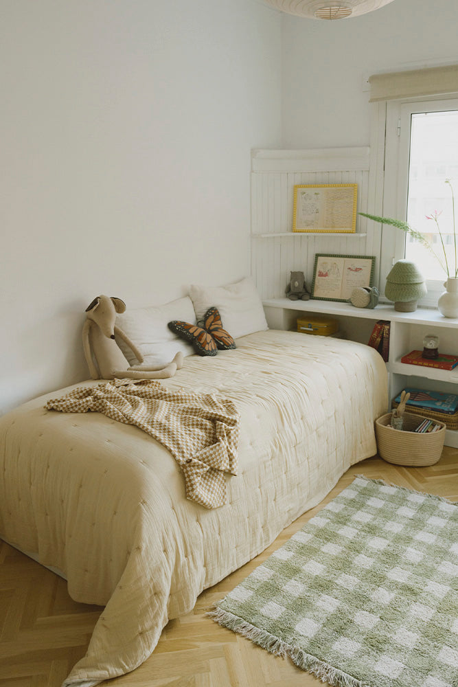 Cozy bedroom with a honey checked throw blanket, bed, plush toys, and a green checkered rug.