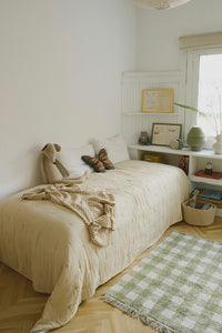 Cozy bedroom with a honey checked throw blanket, bed, plush toys, and a green checkered rug.