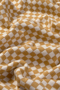 Close-up of a checkered throw blanket with honey yellow and white squares.