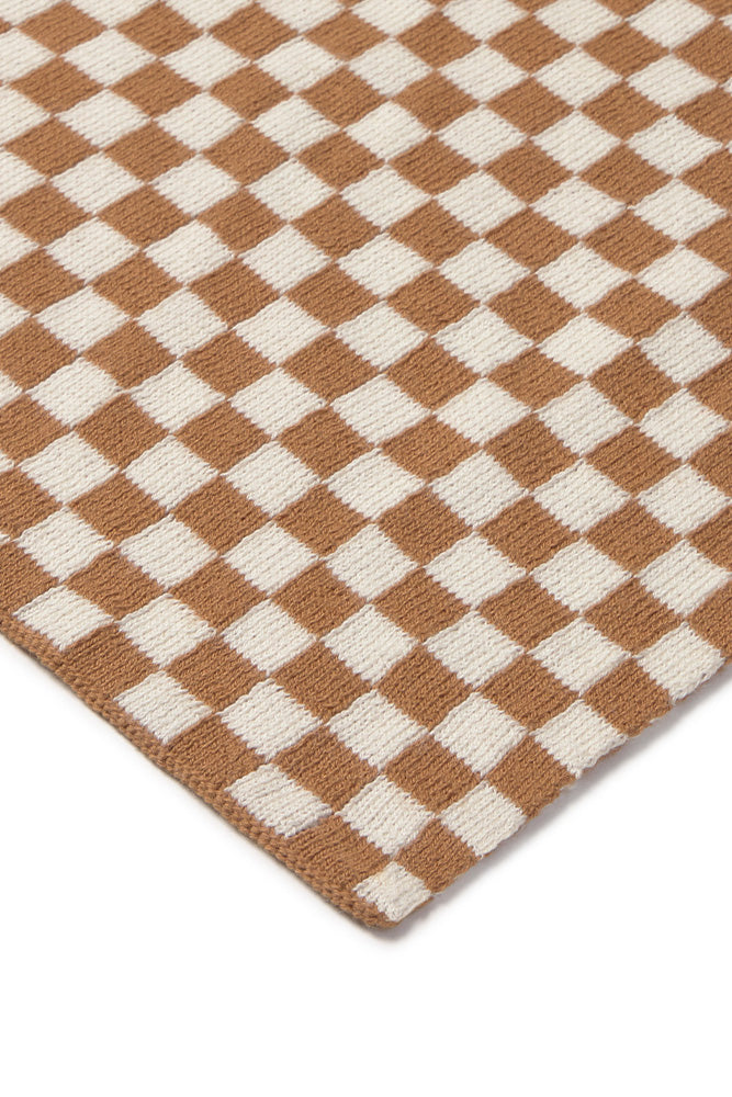 Close-up of a checkered throw blanket with brown and white squares.