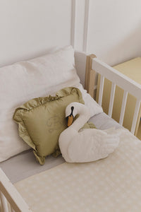 White swan plush pillow on a bed with a ivory checked blanket