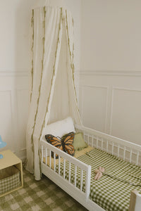 Children's bedroom with a toddler bed, butterfly pillow, and checkered green blanket.