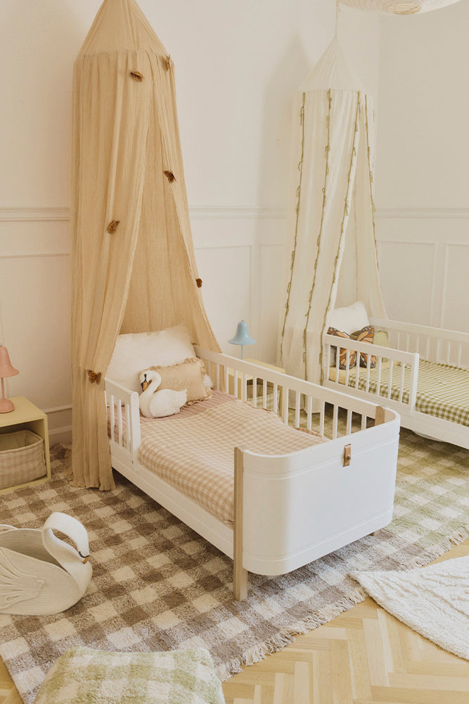 Children's bedroom with a toddler bed, checkered blankets and checkered rugs.