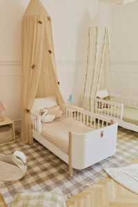 Children's bedroom with a toddler bed, checkered blankets and checkered rugs.