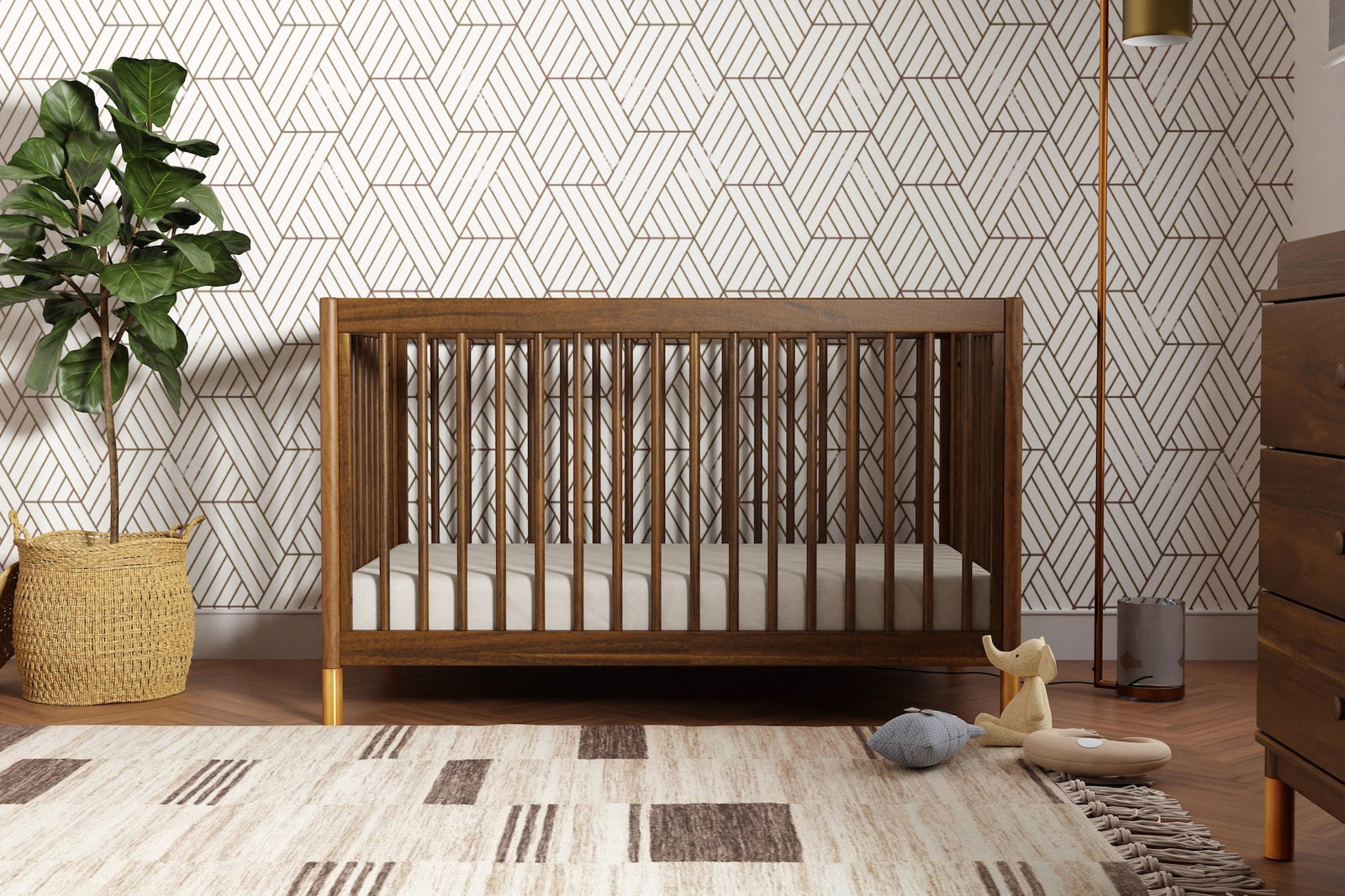 Wooden crib in a nursery with geometric wallpaper and decorative items.