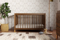 Wooden crib in a nursery with geometric wallpaper and decorative items.