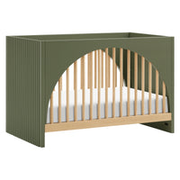 A Moab 3-in-1 Convertible Crib with arched front and back panels in green and beige colors, with a white mattress pad.