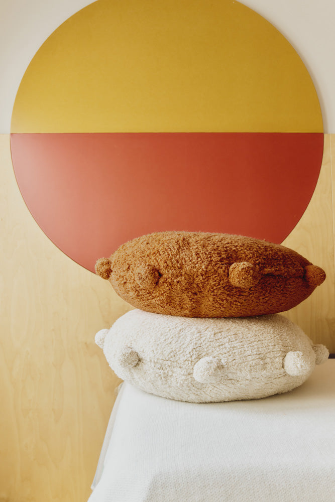 Round orange and natural floor cushions edged with pom-poms