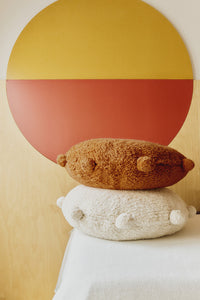 Round orange and natural floor cushions edged with pom-poms