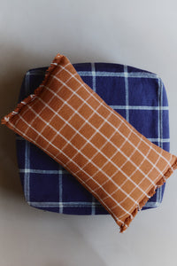 Terracotta checked throw pillow on top of navy pouf