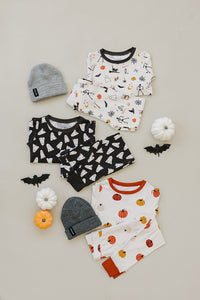 Children's Halloween-themed clothing set with shirts, pants, and hats on a neutral background.