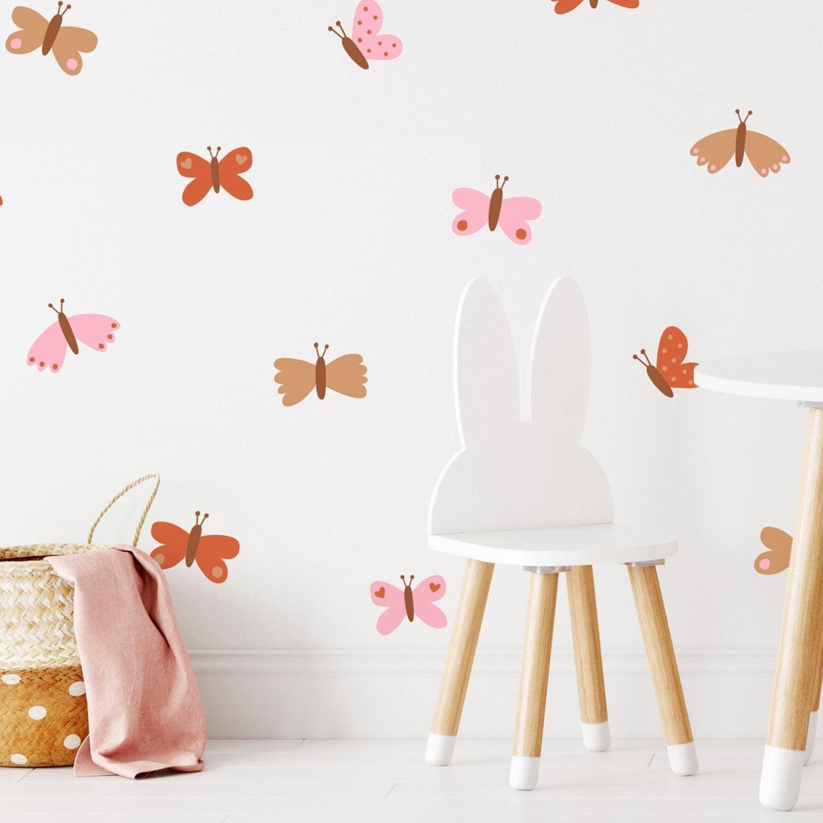 A room with white walls adorned with colorful butterfly wall decals, featuring a chair and a basket in the foreground.